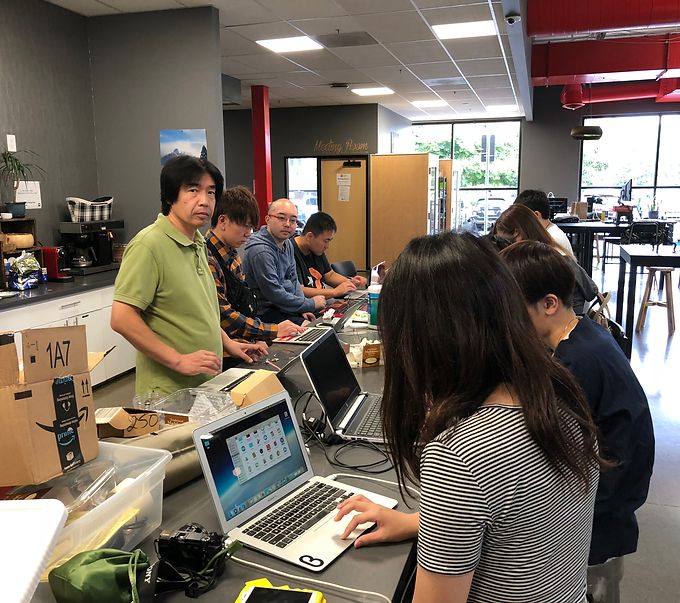 Students working at laptops while a mentor stands nearby