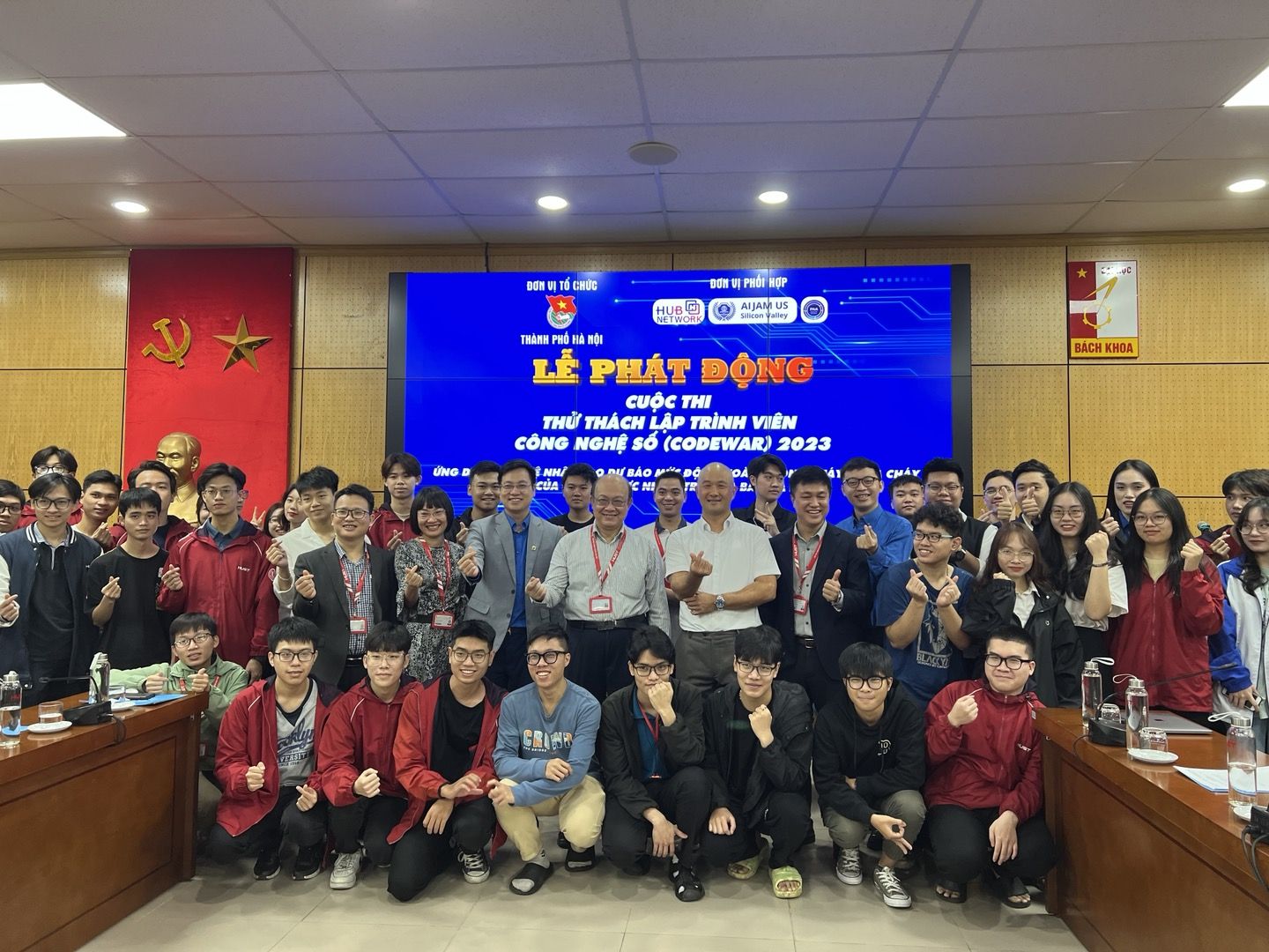 Large group of Vietnamese students and guests posing in front of a stage screen in Hanoi