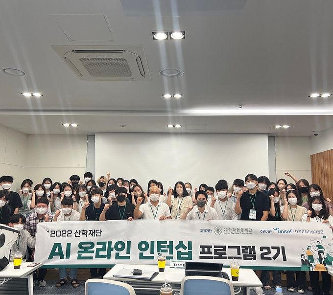 Large group of students posing behind a program banner in a classroom