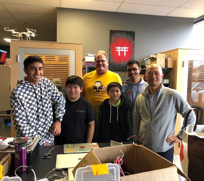 Students and mentors standing behind a workbench with drones and laptops