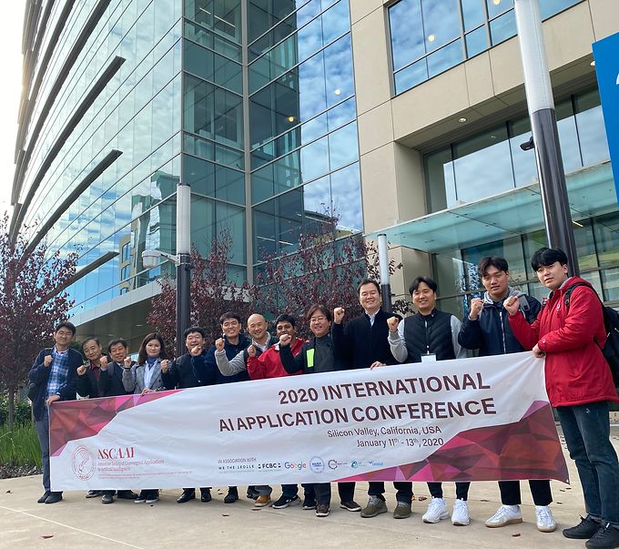 Participants holding a conference banner outside a glass office building