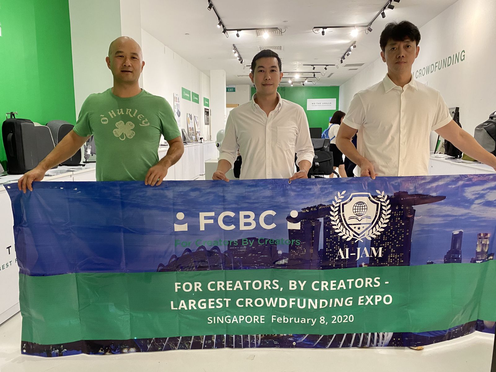 Three people holding a banner at a creators crowdfunding expo in Singapore
